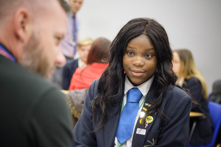 Female secondary student listening to a volunteer in school