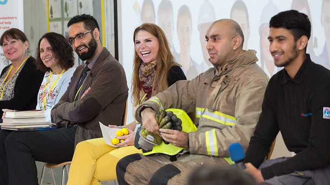 Group of volunteer role models from various jobs sitting in an assembly to interact with pupils
