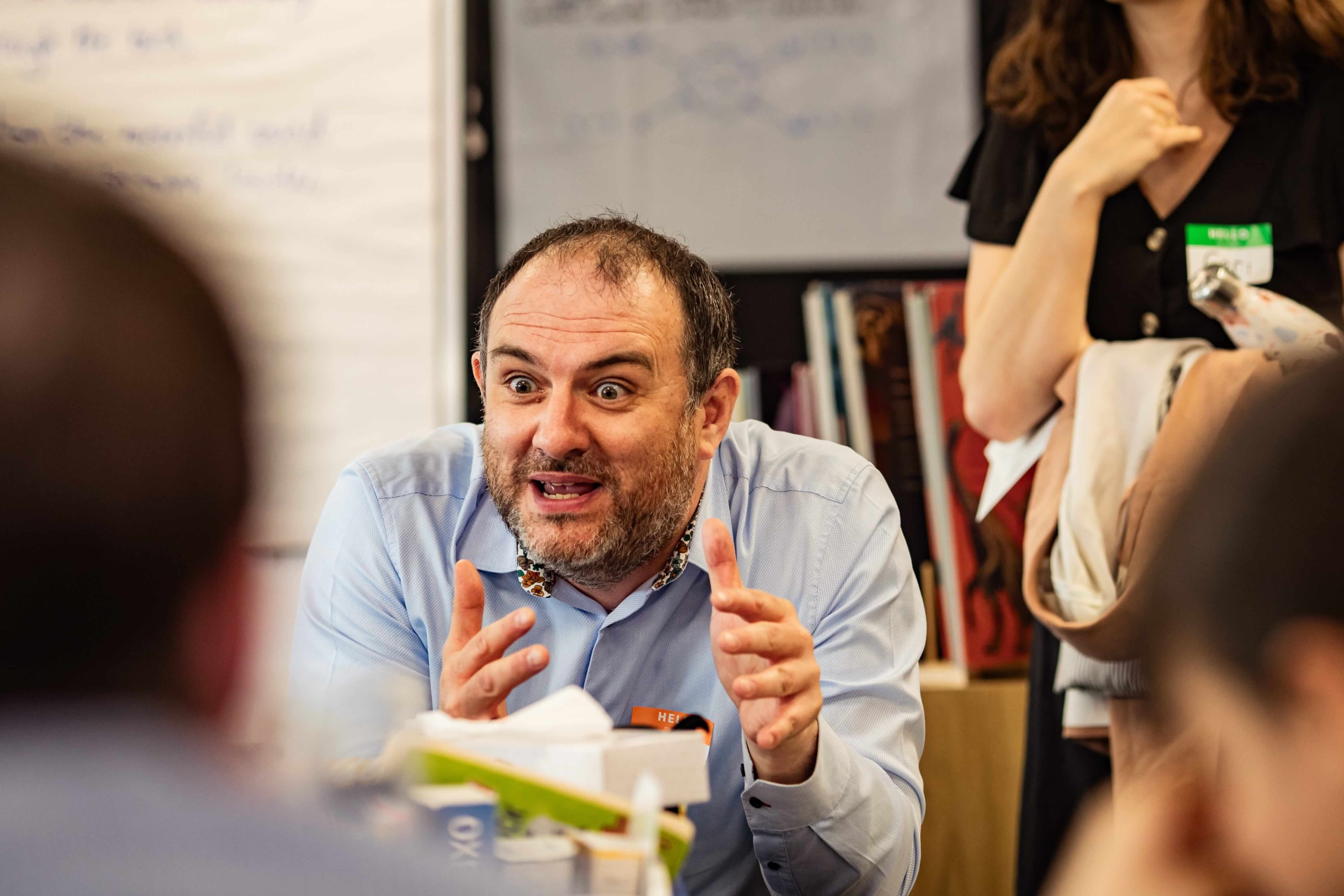 Journalist, Ed, talks animatedly to a small group of primary children in a classroom, about his job in local media.