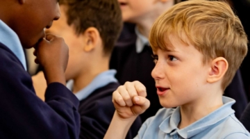 Two young boys from primary schools mock interviewing each other, talking into their pretend microphones as part of Inspiring the Future local media event in Bolton primary school