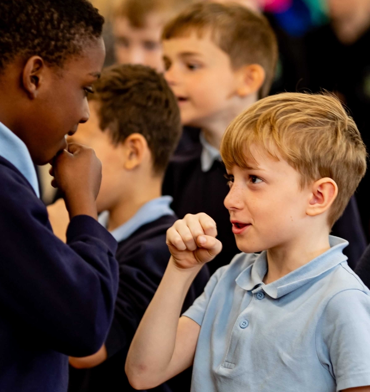Two young boys from primary schools mock interviewing each other, talking into their pretend microphones as part of Inspiring the Future local media event in Bolton primary school
